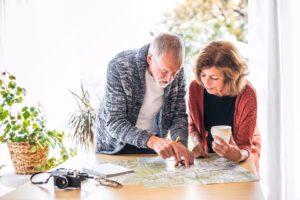 Senior couple with map at home, making plans.